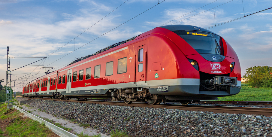 Roter S-Bahn-Zug der Deutschen Bahn auf einer Bahnstrecke unter Oberleitungen.