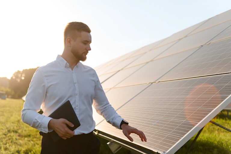 Mann mit Unterlagen vor einer Solaranlage zur Planung und Anmeldung einer PV-Anlage beim Finanzamt.