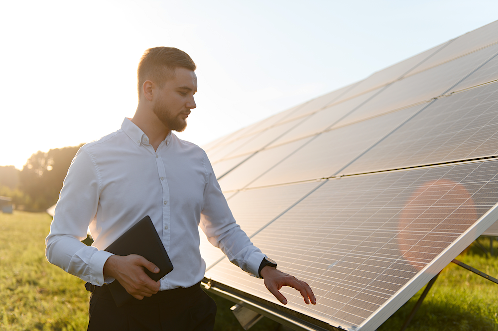 Mann mit Unterlagen vor einer Solaranlage zur Planung und Anmeldung einer PV-Anlage beim Finanzamt.